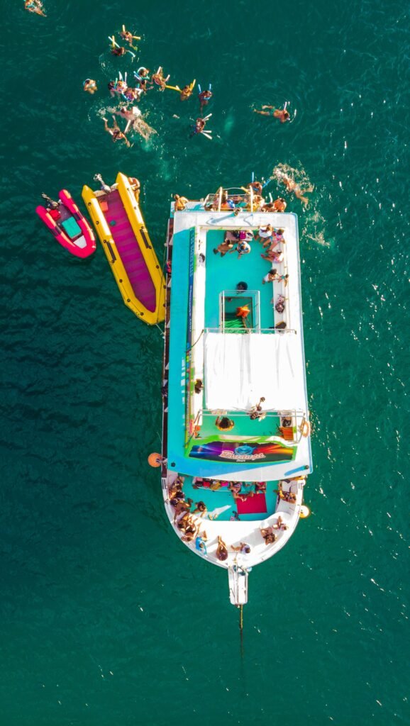 Vibrant aerial view of a boat party with inflatable boats on the ocean in Arraial do Cabo, Brazil.