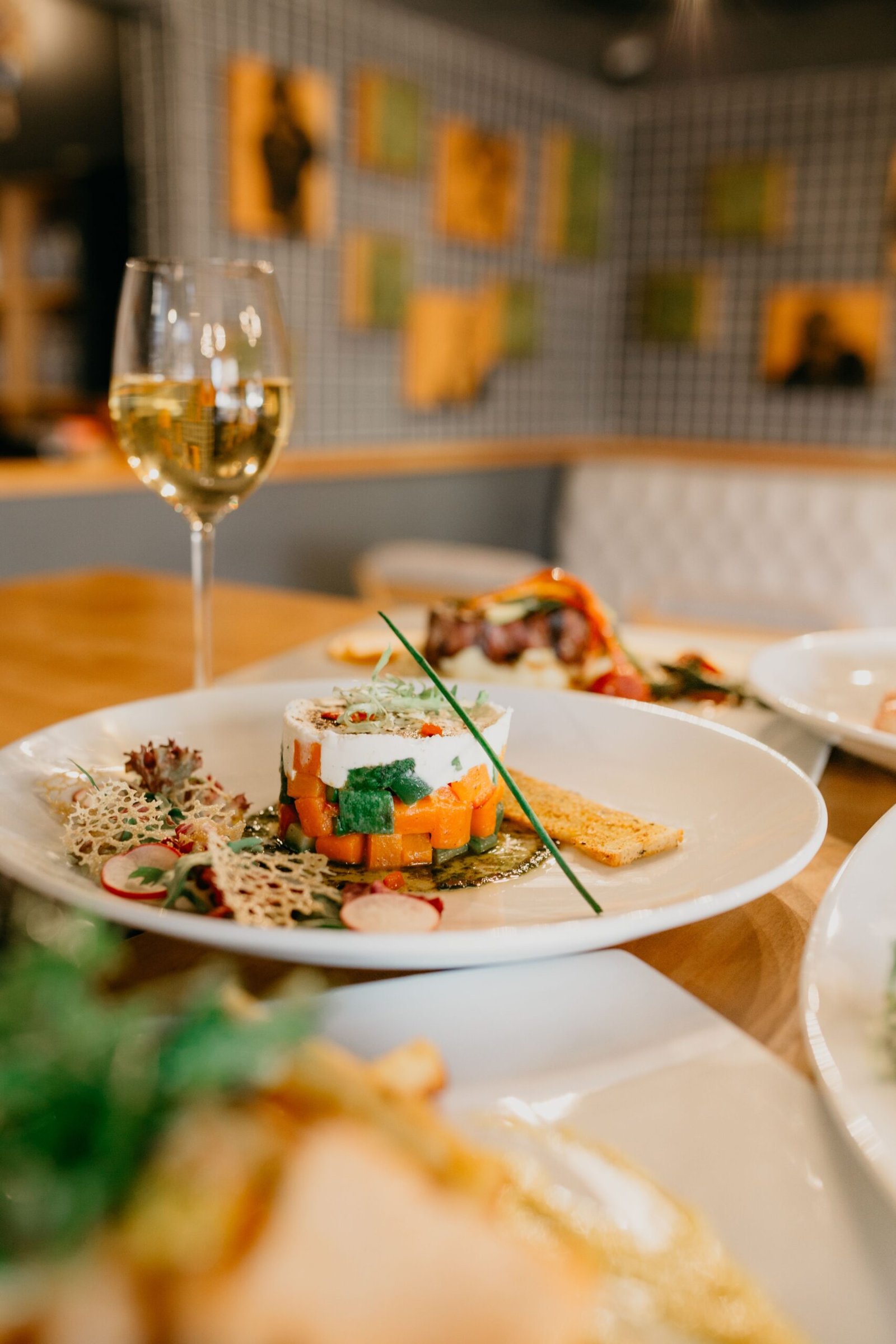 Gourmet dish presented in a fine dining setting with a glass of white wine.
