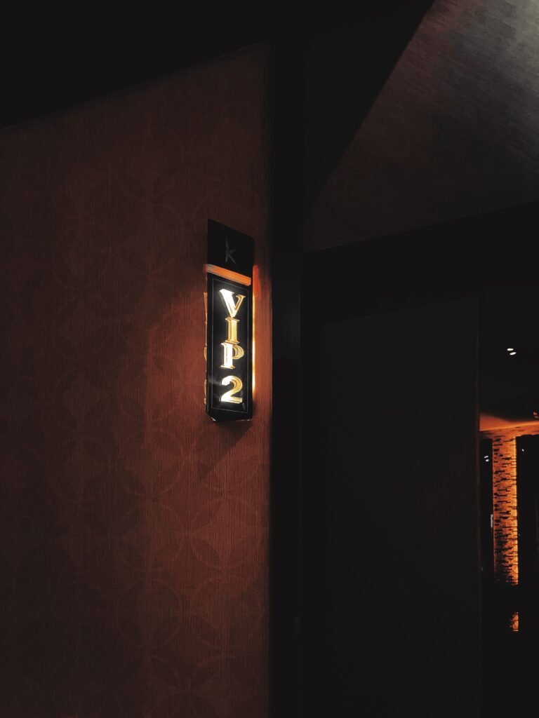 A vertical shot of an illuminated VIP entrance sign in a dimly lit room.