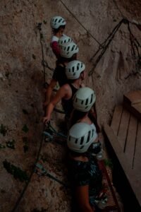 A group of climbers with helmets scaling a rock wall in an outdoor adventure setting.