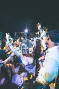 Vibrant outdoor party with a crowd dancing under night lights, featuring a lively atmosphere.