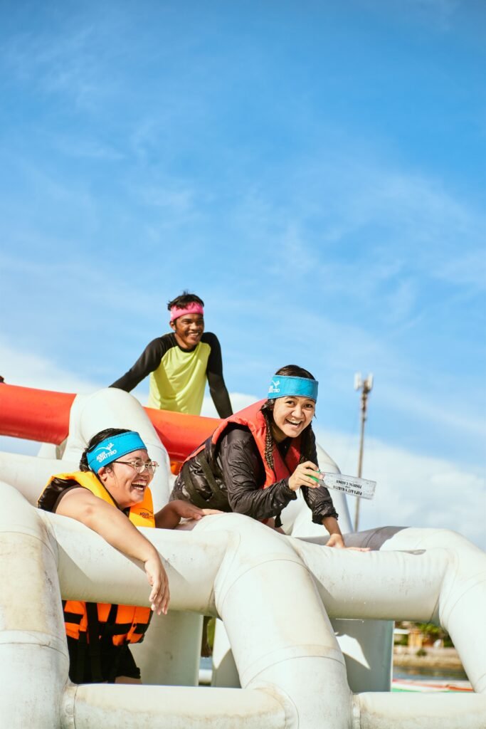 Three adults having fun on an inflatable water obstacle on a sunny day.